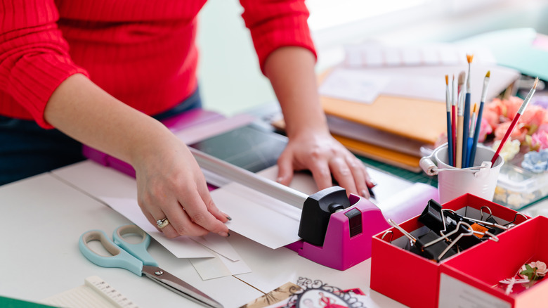 Kağıt kesici ile beyaz kağıdı kesen kadın