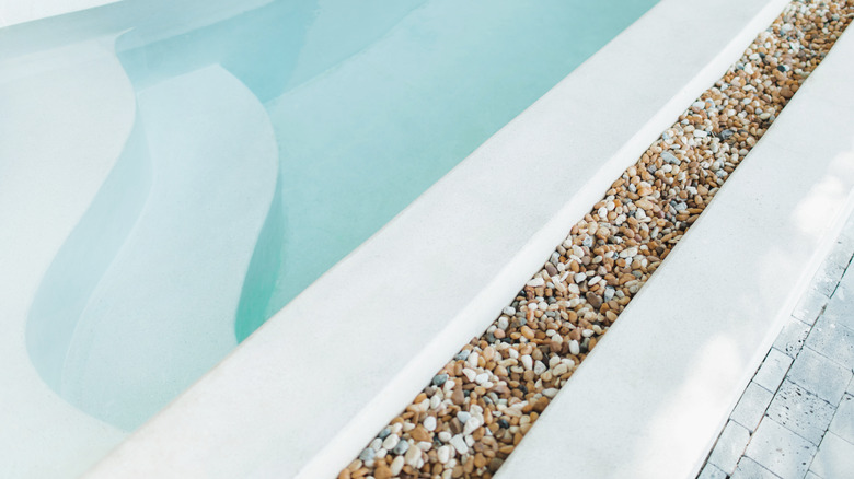 Dekoratif nehir kayalarının sınırına sahip bir yüzme havuzu.