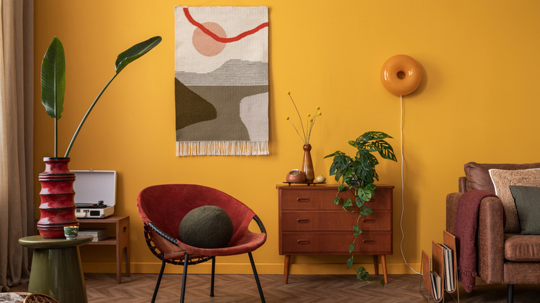 Kırmızı, kahverengi ve turuncu gibi çeşitli sıcak tonların yanı sıra yeşil elementlerin patlamaları ile oturma odası dekoru