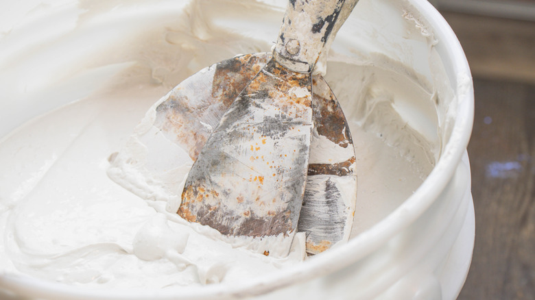 Beyaz bir arka plana karşı bir mala tutan eldivenli bir el.