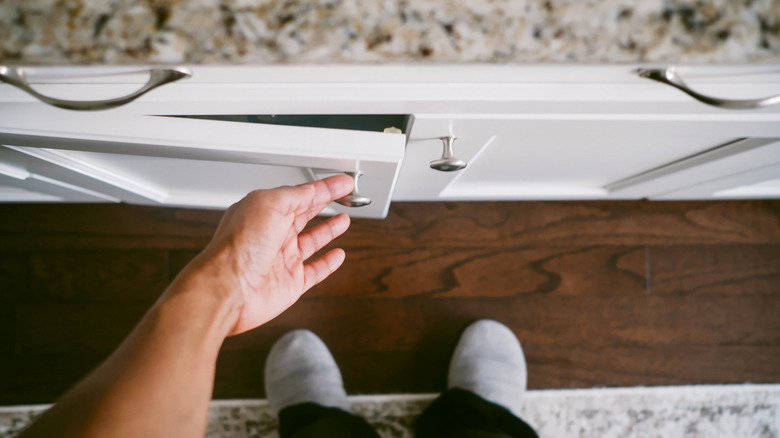 Gümüş düğmelerli beyaz bir dolap açan bir adam