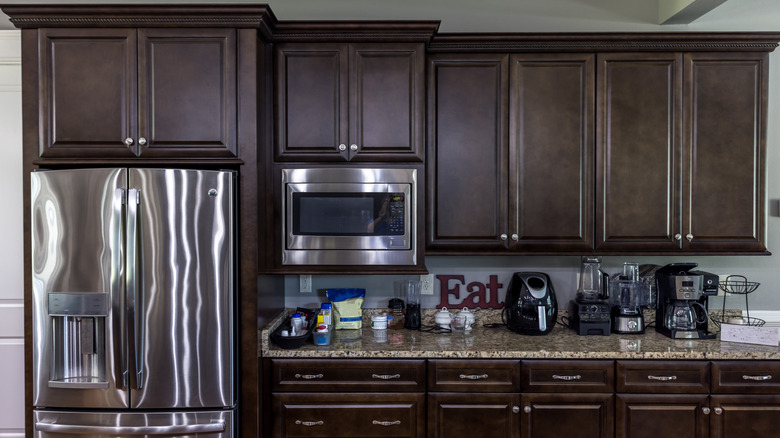 Paslanmaz çalma aletleri ve koyu ahşap dolapları olan mutfak