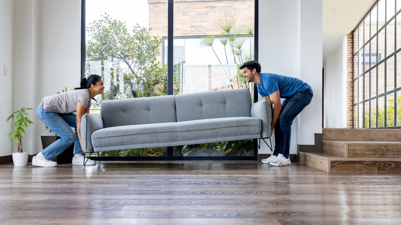 Bir odaya kanepe taşıyan erkek ve kadın