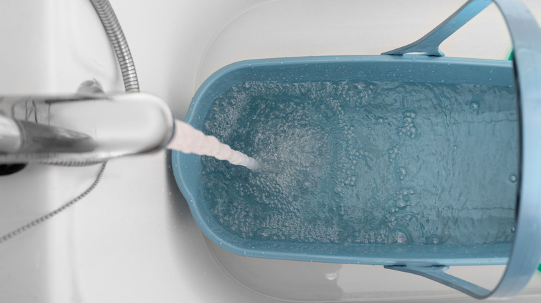 Temiz su banyo musluktan saplı mavi bir kovaya akar