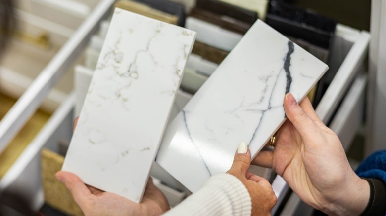Showroom'da beyaz mermer karo örnekleri tutan eller