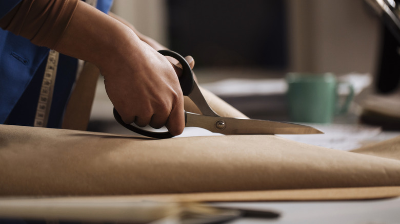 Bir kişi kumaşı makasla keser