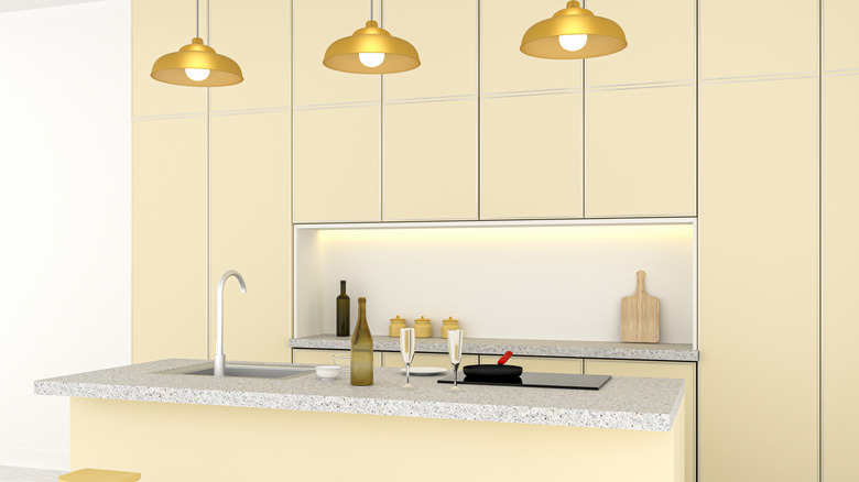 Soluk sarı dolapları ve gri mermer tezgahlı mutfak