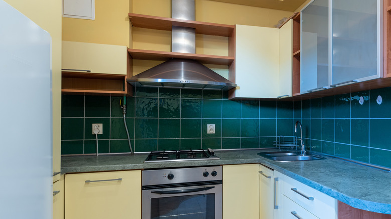 Sarı dolaplı mutfakta koyu deniz mavisi karo backsplash