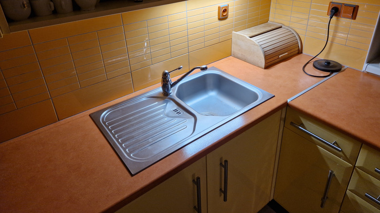 Sarı dolapları ve bal-kahverengi tezgahlı mutfak