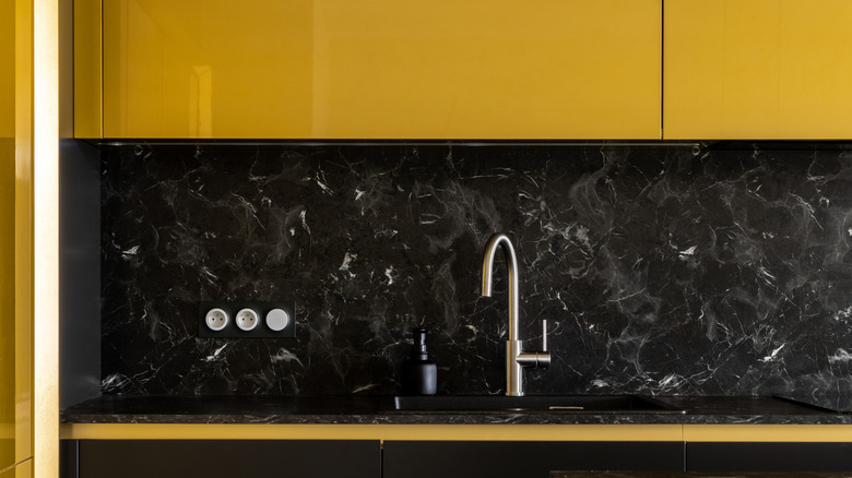 Sarı dolapları ve siyah backsplash ile mutfak