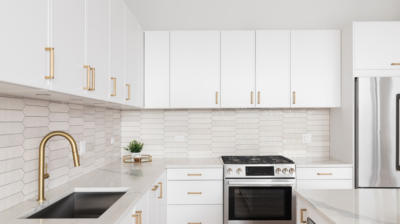 Tepegöz dolaplarının altında, tamamen beyaz bir mutfakta beyaz backsplash