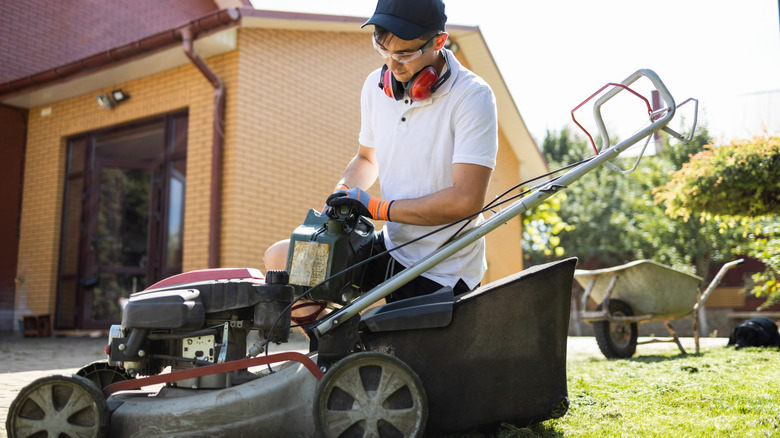 Bir çim biçme makinesini benzinle dolduran bir adam