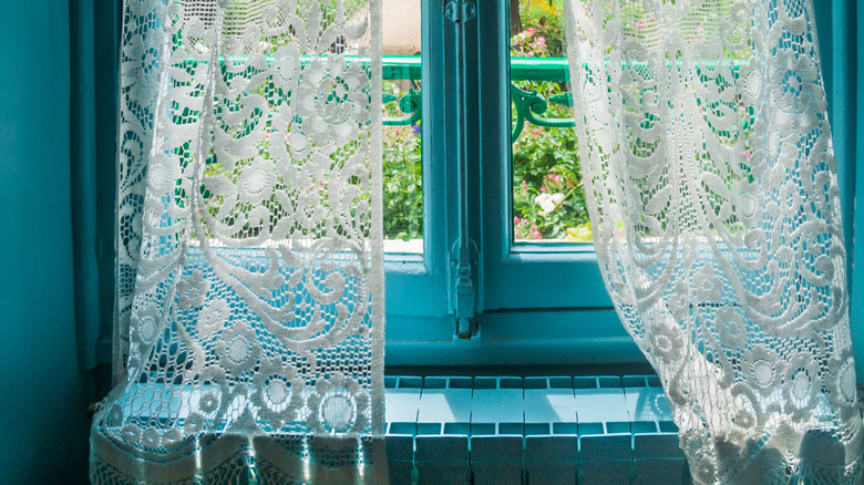 Mavi duvarlarla pencerede dantel perdeler