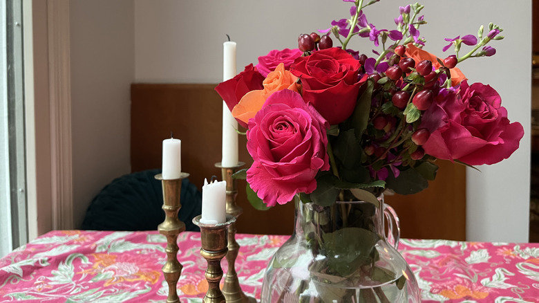 Masadaki çiçeklerin yanında pirinç şamdanlar
