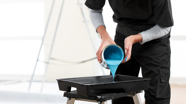 Mavi boya siyah bir tepsiye döken biri.