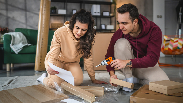 Yeni dairede hareket eden genç bir çift, mobilya monte etmek