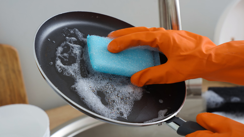 Siyah yapışmaz bir tava el yıkayan biri.