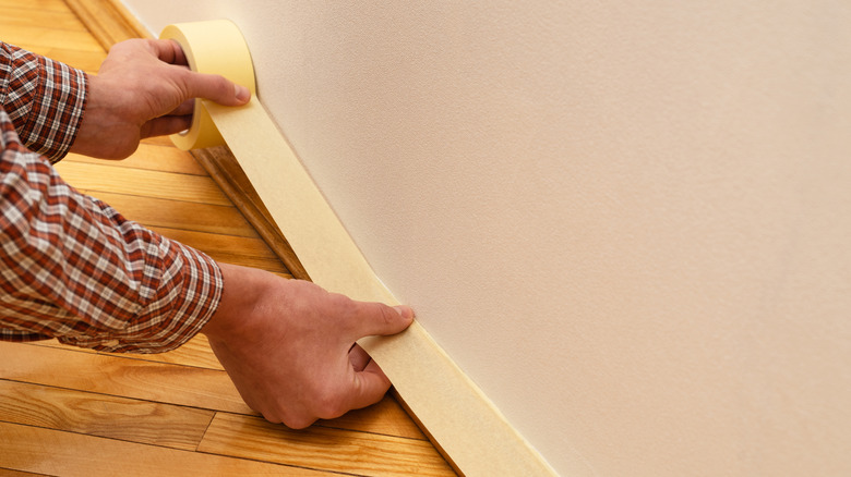 Resim yapmadan önce süpürgelikten bantlayan bir adam