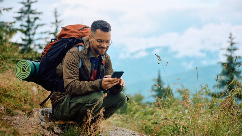 Erkek backpacker zammı üzerinde cep telefonu izleme