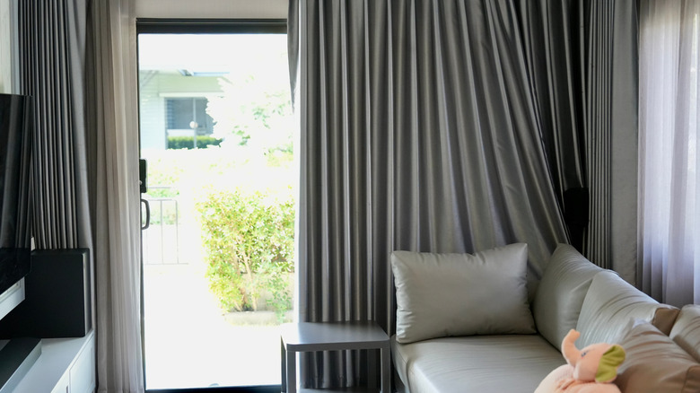 Küçük oturma odasında büyük gri perdeler ile kayar cam kapı