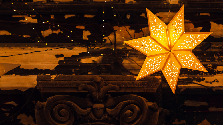 Dekoratif kağıt ışığı, geleneksel süslemeli bir yıldız şeklinde vintage odada bir duvara asılır.