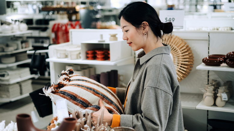 Ev dekoru için alışveriş yaparken yastığa bakan kadın