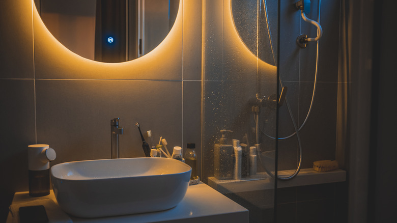 Ayna ışığı ile aydınlatılmış loş, karamsar bir banyo