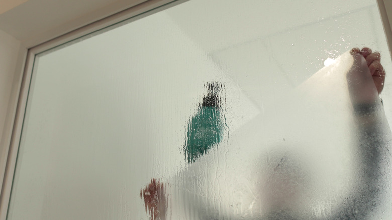 pencereye buzlu bir cam film koyan bir kişi