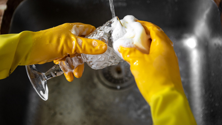 Bir bardak temizleyen sarı eldiven giyen bir kişinin closeup