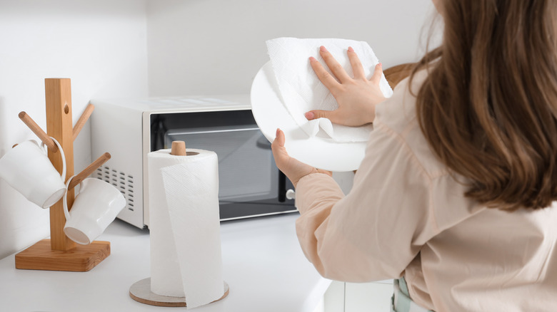 Kadın bir kağıt havlu ile bir tabak kurutuyor