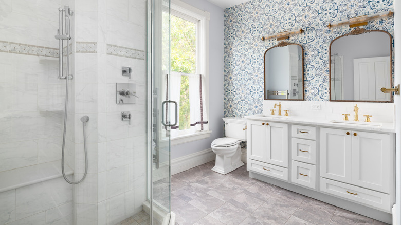 Fayans duvarı ve zeminli banyo, beyaz dolaplar ve mavi ve beyaz duvar kağıdı