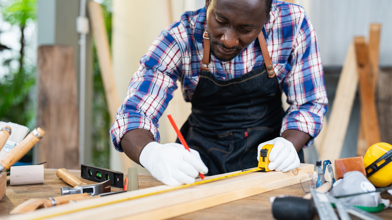 Kesim yapmak için bir tahta işaretleyen kişi
