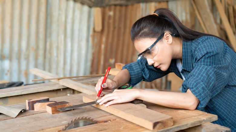 Bir cetvelle ahşabı işaretleyen bir kişi