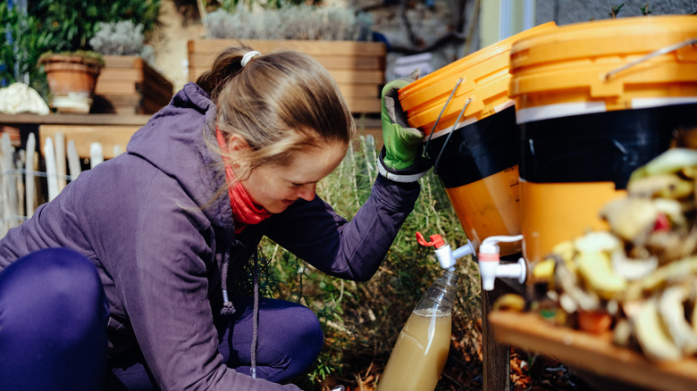 Bokashi kovasından bir şişeye sıvı boşaltan genç kadın