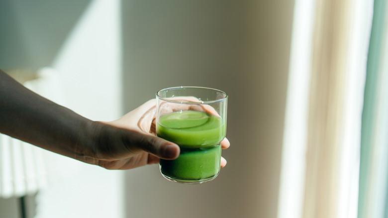 Bardak yeşil meyve suyu tutan kadın
