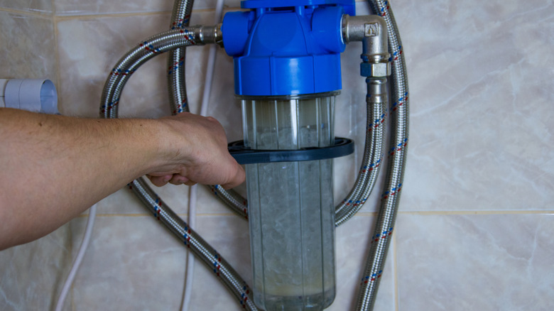 Evde su yumuşatıcı filtresini değiştiren bir kişi