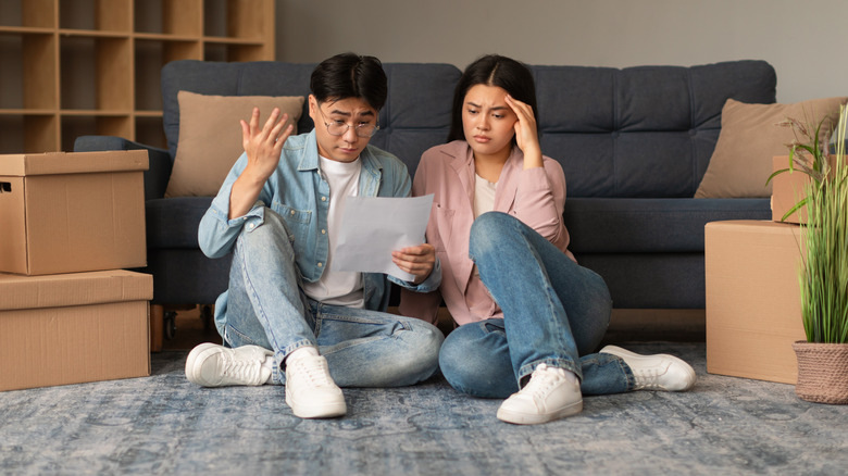 Bir çift, hareketli kontrol listesine bakarken bir kanepenin yanında oturuyor