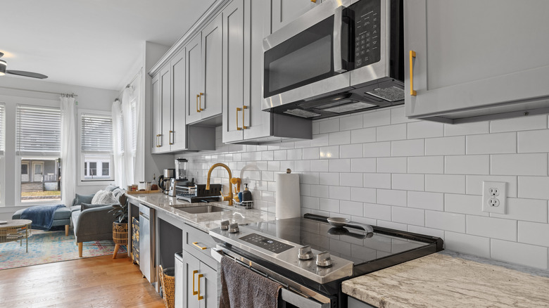 Şık paslanmaz çelik aletler, tezgahlar ve ahşap döşeme ile modern mutfak.