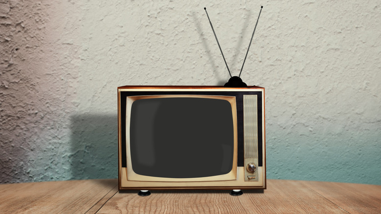 Ahşap bir masada anten içeren retro bir TV.