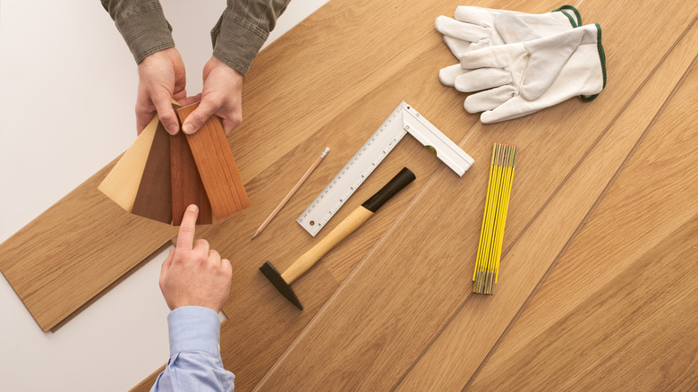 Arka planda çalışma aletleri olan renk örneklerinden ahşap döşeme seçeneği seçen bir kişi