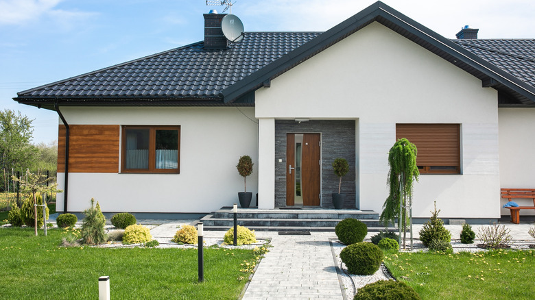 Beyaz dış, siyah çatı ve ahşap kapı ile ev
