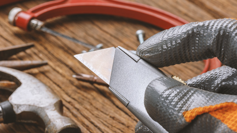 Metal geri çekilebilir bir bıçak tutan el