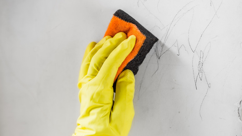 Bir kişi mum boya çizimlerini duvara temizler