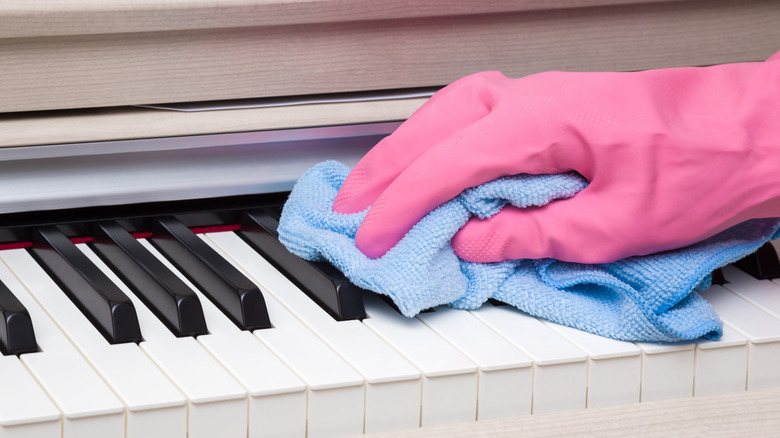 Bir kişi piyano anahtarlarını bir bezle temizler