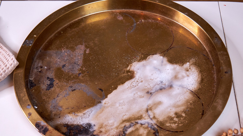 Kirli bir pirinç tabak sabunlu su ile doldurulur