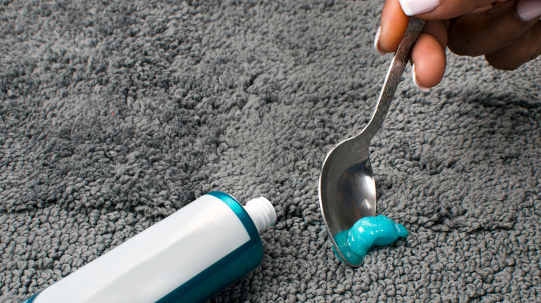 Bir kişi halıyı diş macunu ile temizler