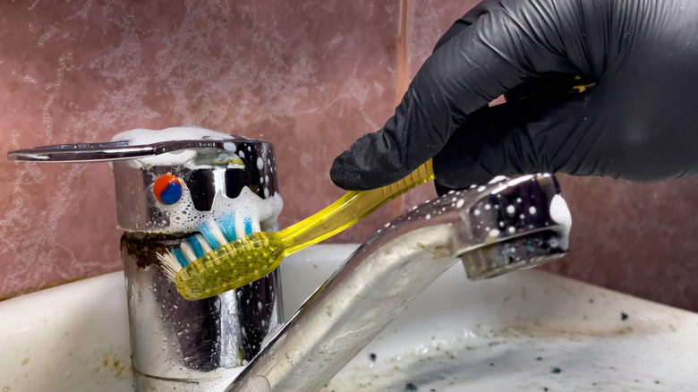 Bir kişi diş macunu ile sert suyu temizler