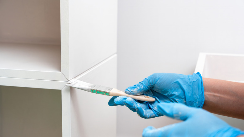 Eldivenli eller eski mobilya çatlakları bir fırça ile boyamak