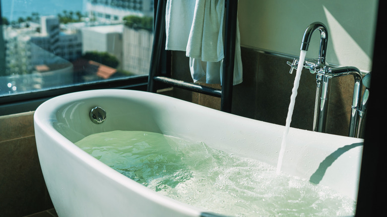 Musluktan gelen su ile kısmen doldurulmuş zarif bir küvet.