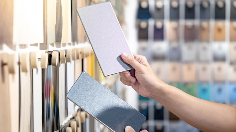 Tasarımcı elleri malzeme kütüphanesinde yakındaki malzeme renk örneği duvar ekranını yakındaki iki gri laminat kağıdı karşılaştırın.